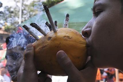 A youth smokes marijuana cigarettes using a papaya during a rally in support of legalizing marijuana in Medellin, Colombia, May 2013. AP Photo, Luis Benavides